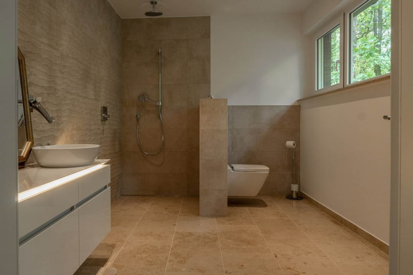 Entwurf im Waldhaus, Mönchengladbach-Hardt — Bad mit bodengleicher Dusche und freistehendem WC, Wände und Boden in hellem Travertin