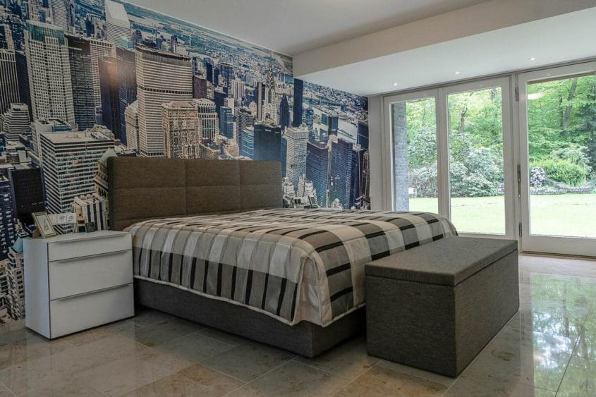 Entwurf im Waldhaus, Mönchengladbach-Hardt — Schlafzimmer im Waldhaus mit Doppelbett vor einer Skyline-Tapete und großen Gartenfenstern — Innenarchitektur von Bernd Schüller
